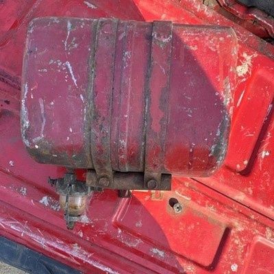 Slitet rött bränslefilter med sedimentkopp på en äldre traktor